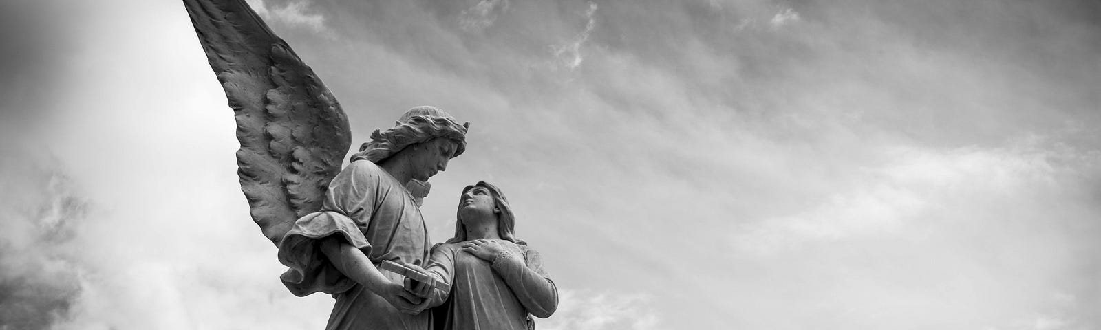 statue of an angel and young woman under cloudy skies