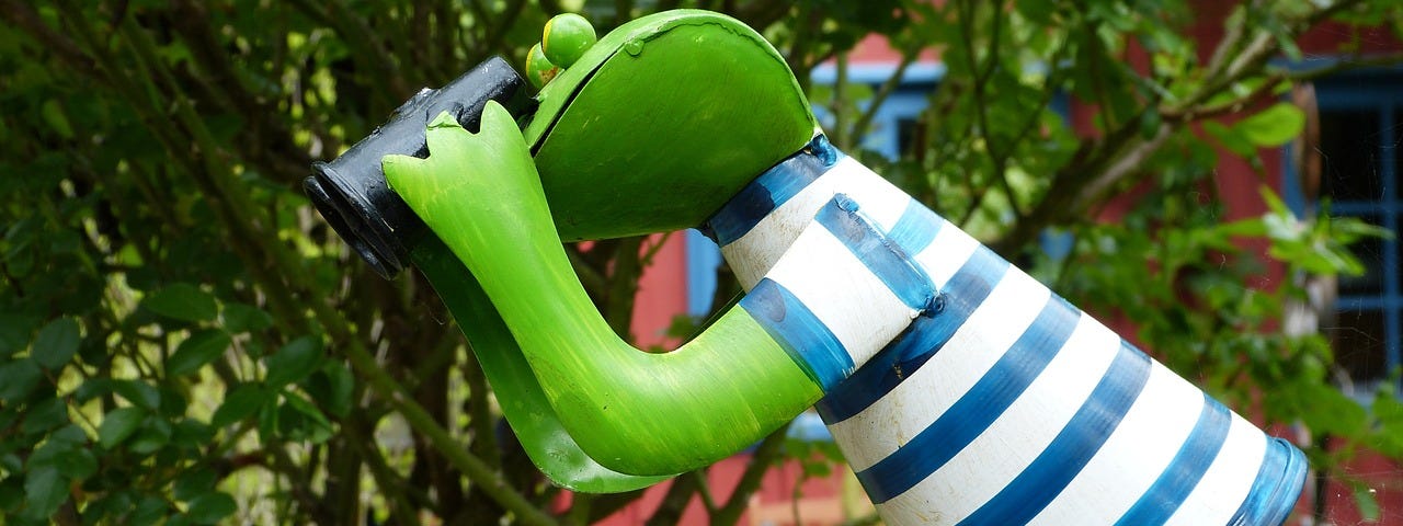 A green frog sculpture with binoculas