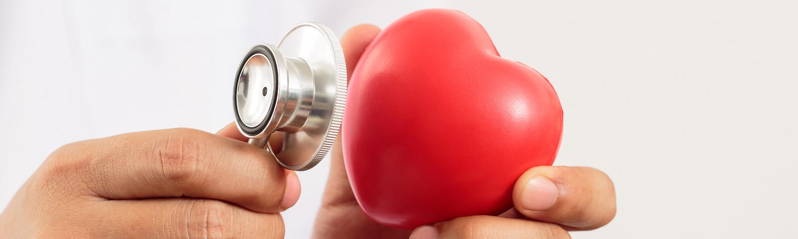 Someone holding a stethoscope and a miniature heart.