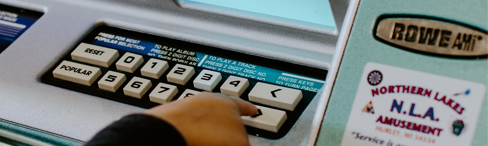 Uma pessoa está pressionando o botão próximo em uma máquina vintage de compra de discos com interface mínima