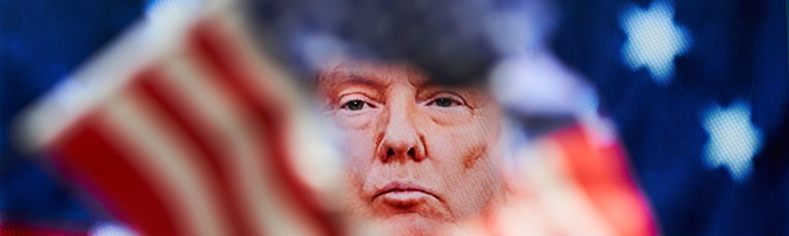 US President Donald Trump’s face shown through a torn US flag