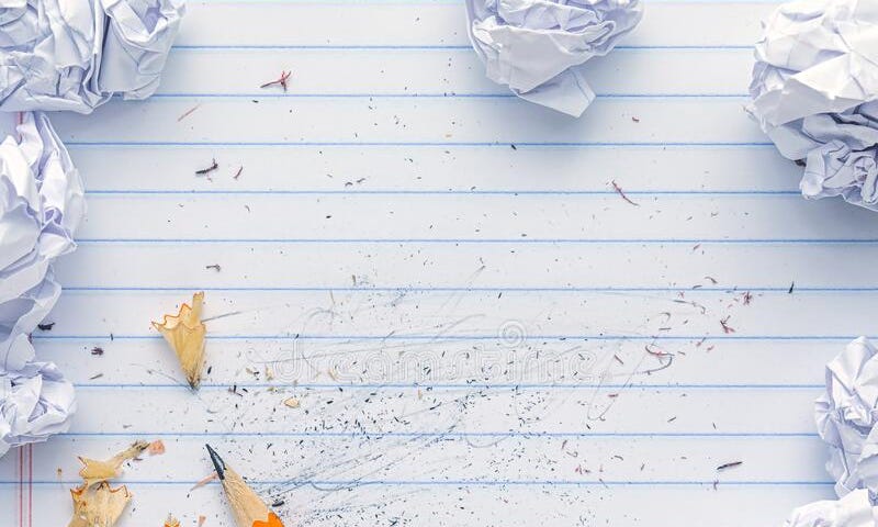 a piece of lined notebook paper with eraser marks, pencil shavings, and crumpled papers on top of it