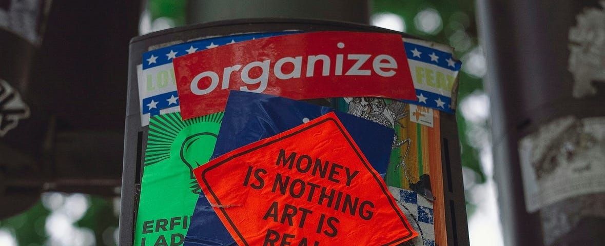 A protest sticker that says, “Money is nothing art is real.”