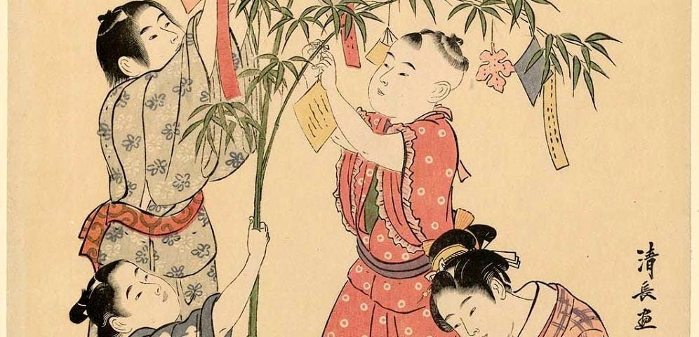 Woodblock print from the 1700s, showing kimono-clad children decorating a bamboo branch with colorful wish papers and decorations. A girl is writing with a brush and inkstone at a low table. Another girl is on the floor reading a book.