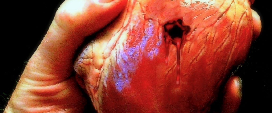 Artistic rendition of a hand holding a human heart with a bleeding hole in it