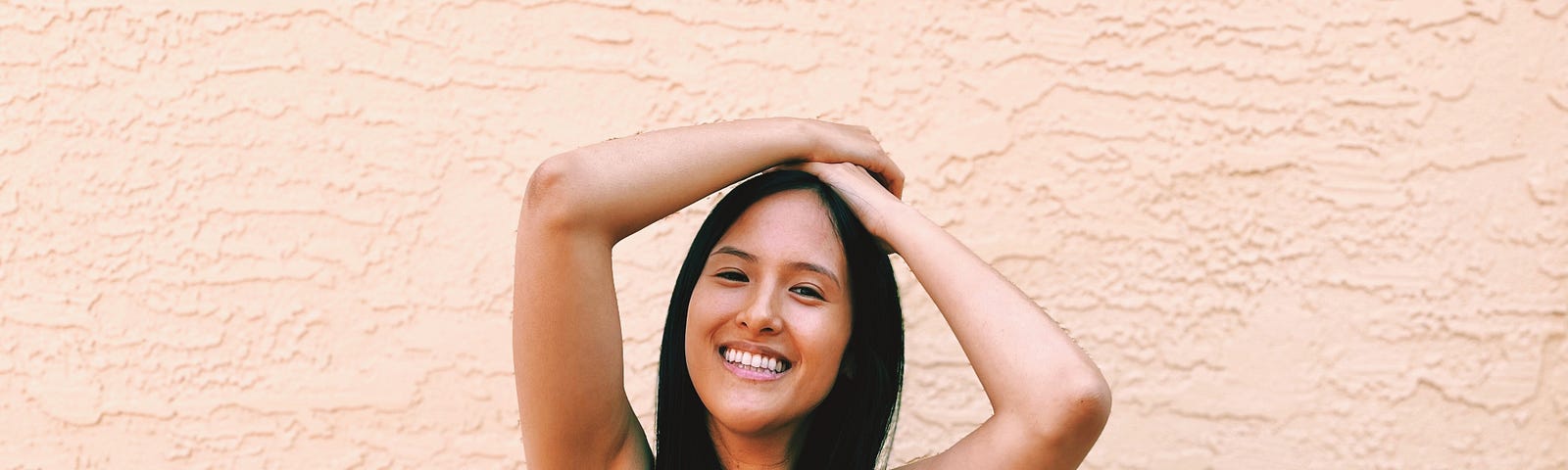 Photo of author with her hands posed above her head showing her unshaved underarms.