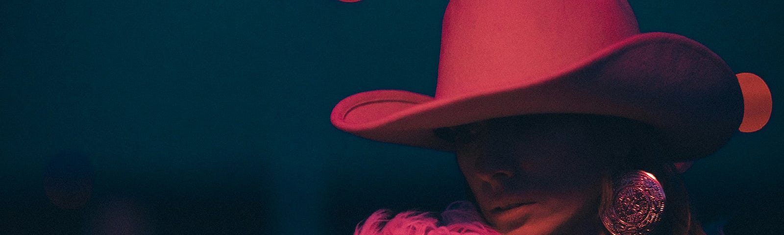 Nighttime photo of a woman wearing a pink cowboy hat.