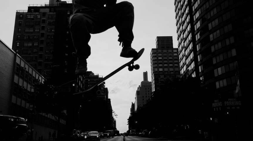 Skateboarder jumping across busy New York street