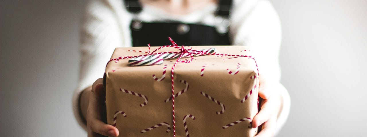 A woman holding out a wrapped gift