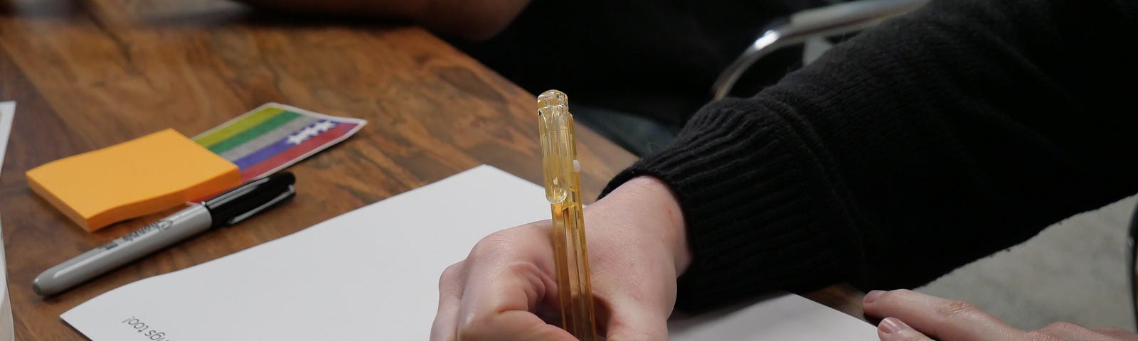 Image of a participant in a black long-sleeved shirt filling out a worksheet with an orange pen.
