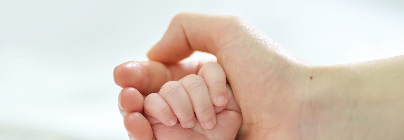 Baby and parent holding hands