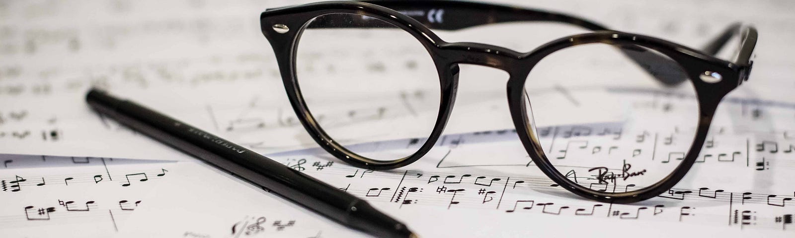 Stock photo of eyeglasses and a pen on top of sheet music, by Dayne Topkin on Unsplash