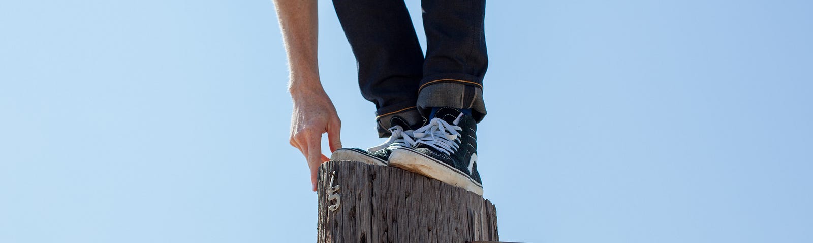 Legs and arms of a person standing on top of a post.