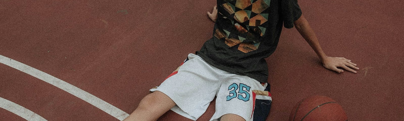 Kid sprawled out on a basketball court.