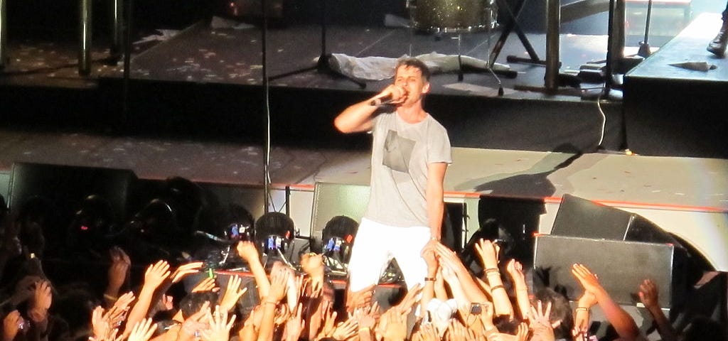 Foster the People frontman Mark Foster stands in the middle of a concert crowd