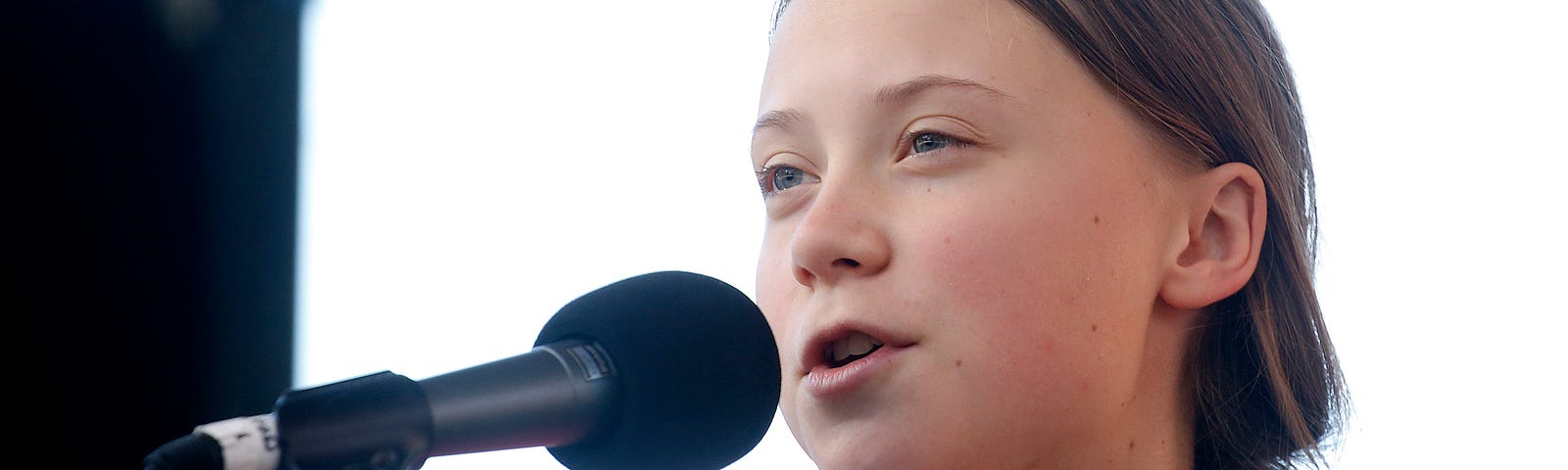 Activist Greta Thunberg speaking into a microphone as she leads the Youth Climate Strike.