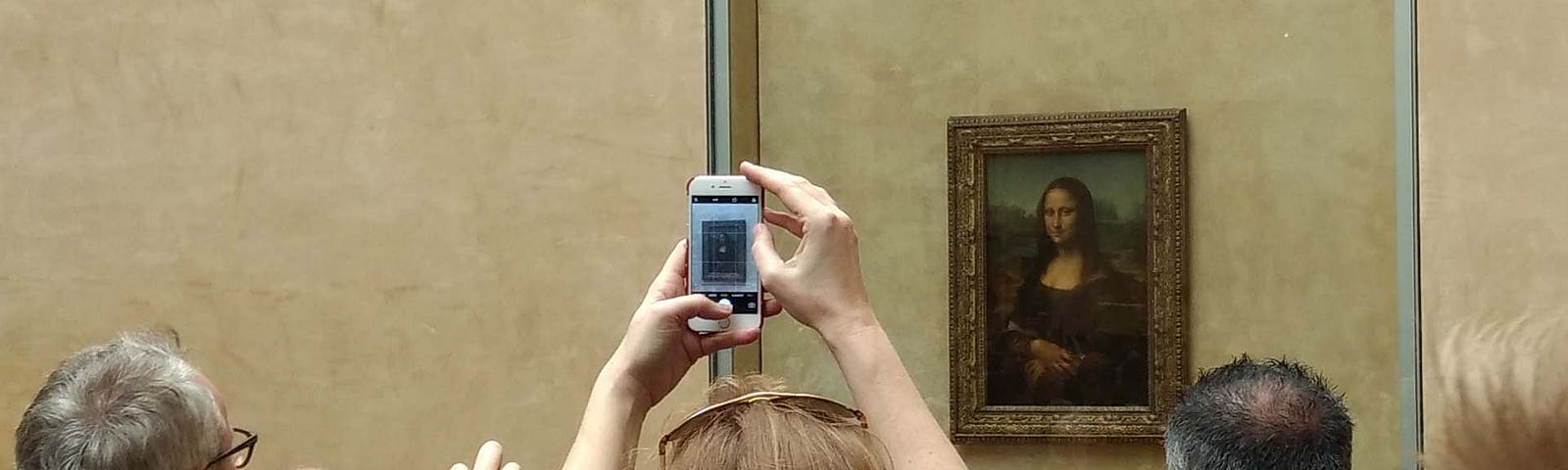 A group of tourists taking pictures of the Mona Lisa with their phones.