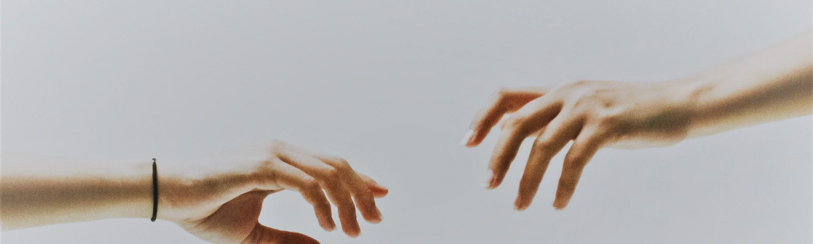 Two hands outstretch toward each other against a white canvas