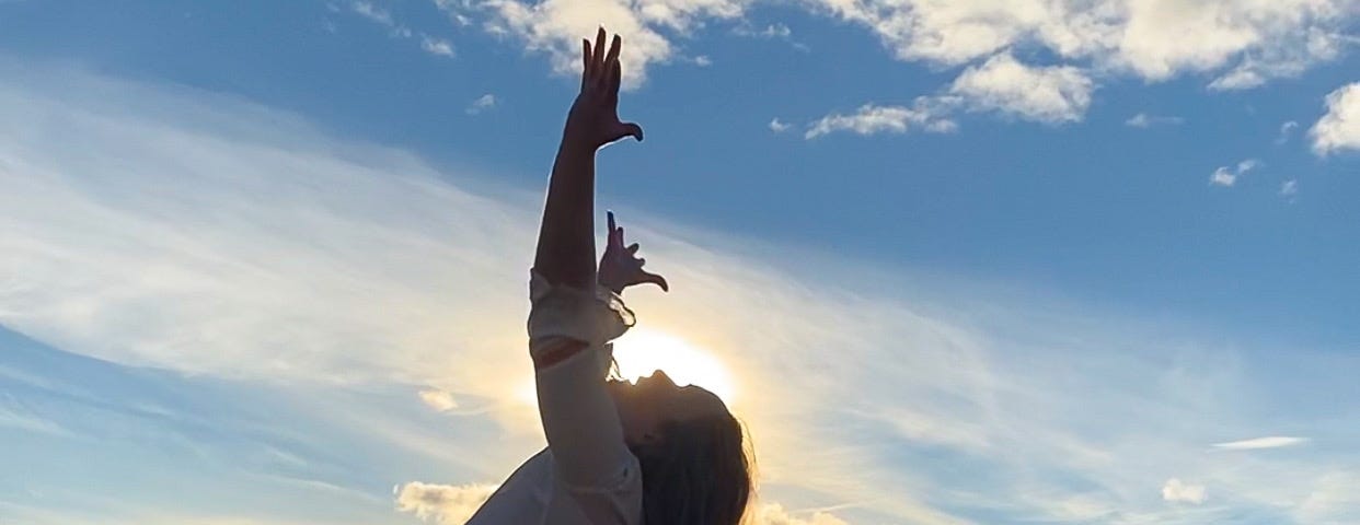 A woman in the mountains stretching out her hands to the sky