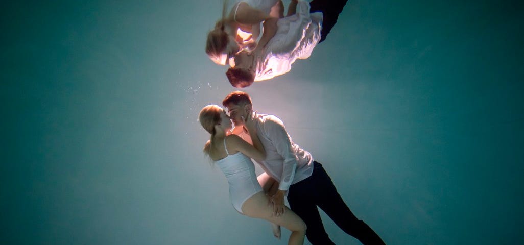 A couple embrace under water.