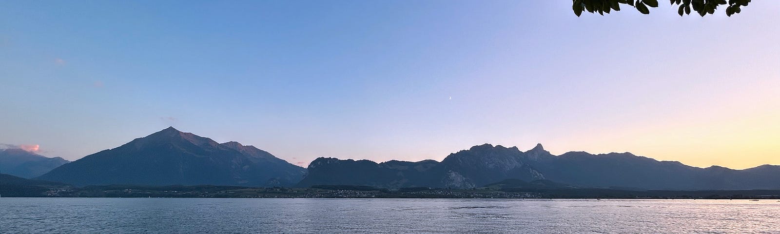 Panoramic views along Lake Thun at sunset. To the left, the famous pyramid-shaped mountain, the Niesen.