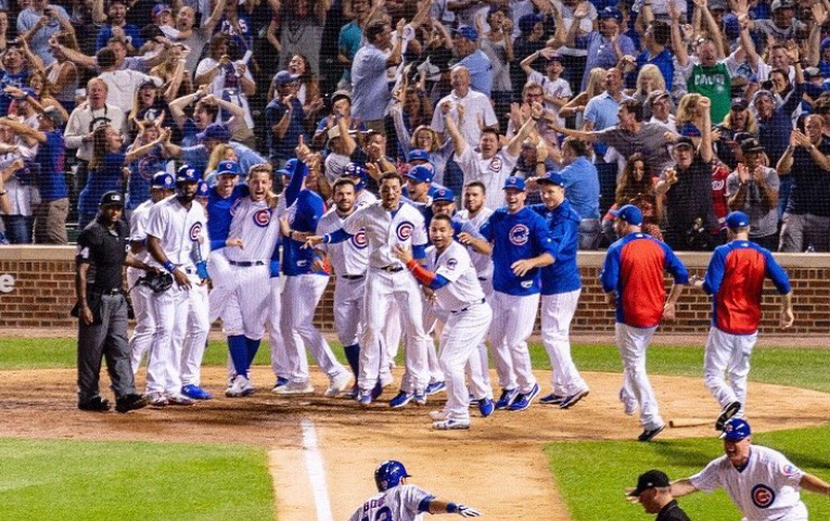 Cubs player running to home plate. Greeted by teammates.