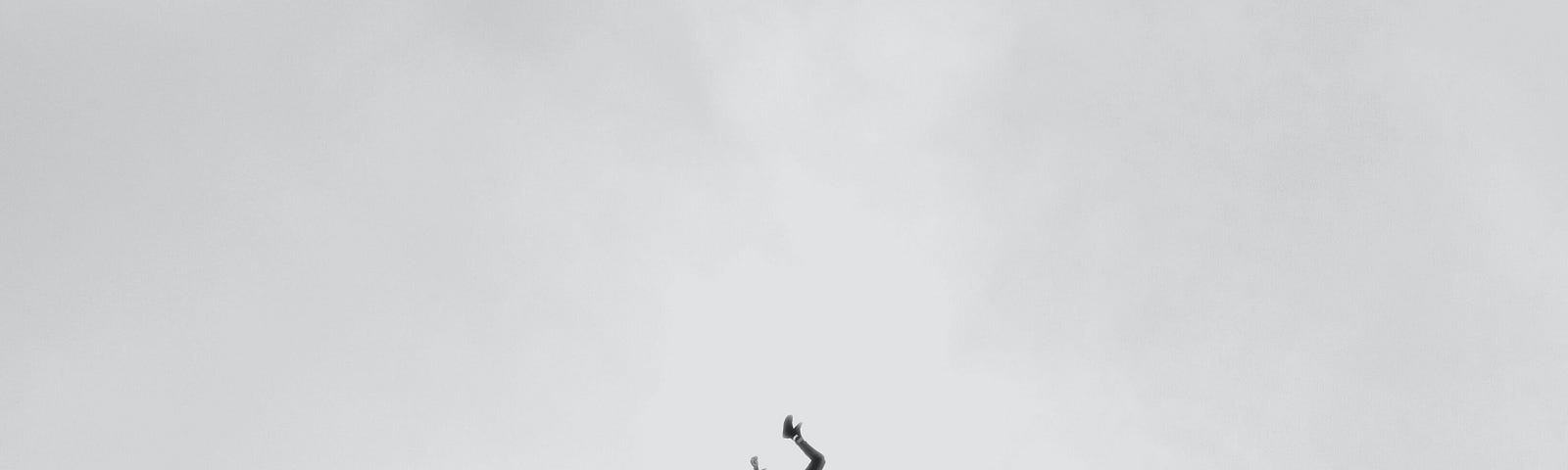 A black and white picture of a man falling from extreme heigth.