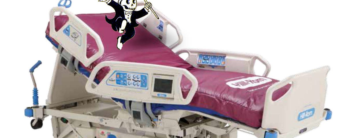 A Hillrom Totalcare Spo2rt 2 Surface hospital bed; it has been modified so that a dancing version of Monopoly’s Rich Uncle Pennybags is dancing on the headrest; he has removed his face and is waving it like a tamborine; his head is a grinning death-skull.