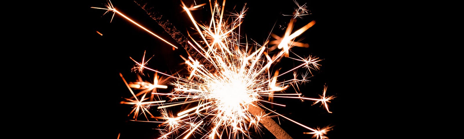 Alt: colour macro photograph of a sparkler burning bright against a dark background. Image credit: Jez Timms | Unsplash