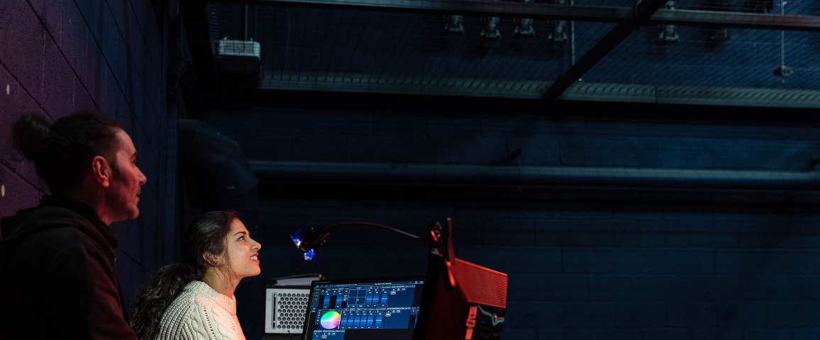 A student and teacher work together on a lighting rig.