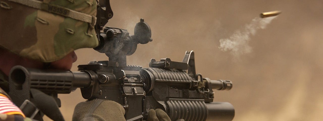 A soldier firing his gun in a war.