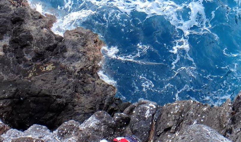 Rachel Rounds ascending rock cliff at Nihoa island
