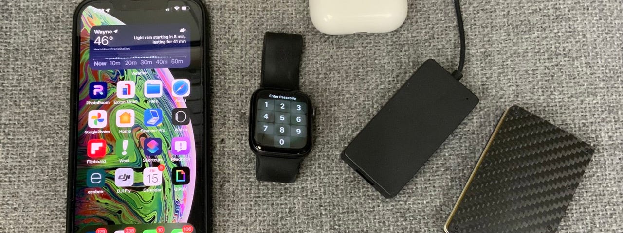 A picture of the most used gadgets used during a typical day. These consist of an iPhone, minimalist wallet, Apple Watch, Airpod Pros, Wireless Carplay, and a Magsafe battery.