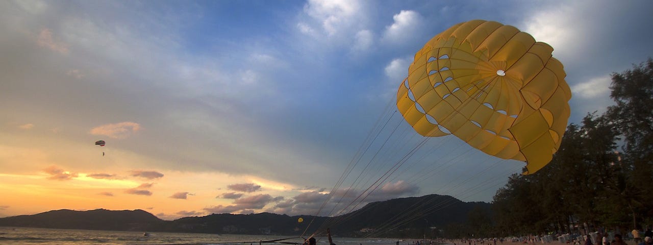 children on the beach with a yellow parasail