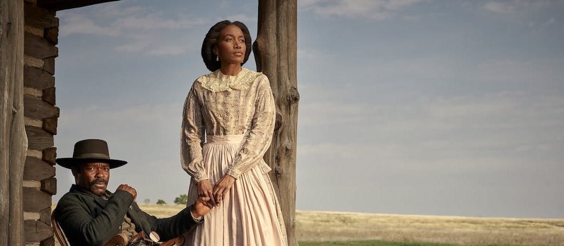 David Oyelowo and Lauren E. Banks as Bass and Jennie Reeves. He sits in a rocking chair while she stands beside him, holding his hand. They are on a porch, and the plains spread behind the fence in the foreground.