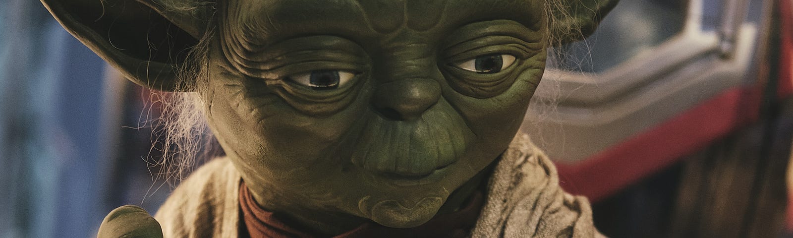 Yoda holding the top of his walking stick with green, clawed fingers