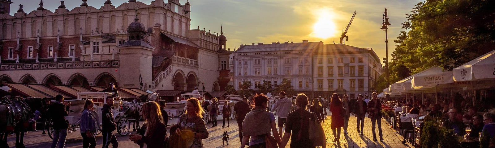 People walking through Main Market Square in Krakow at sunset