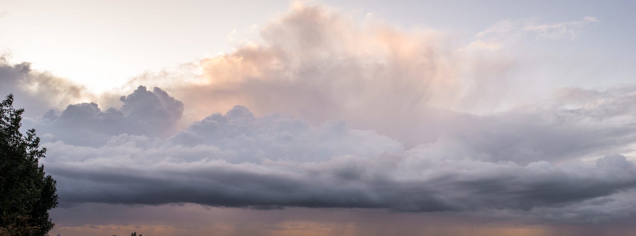 Panoramic photo of approaching storm clouds over farm fields.