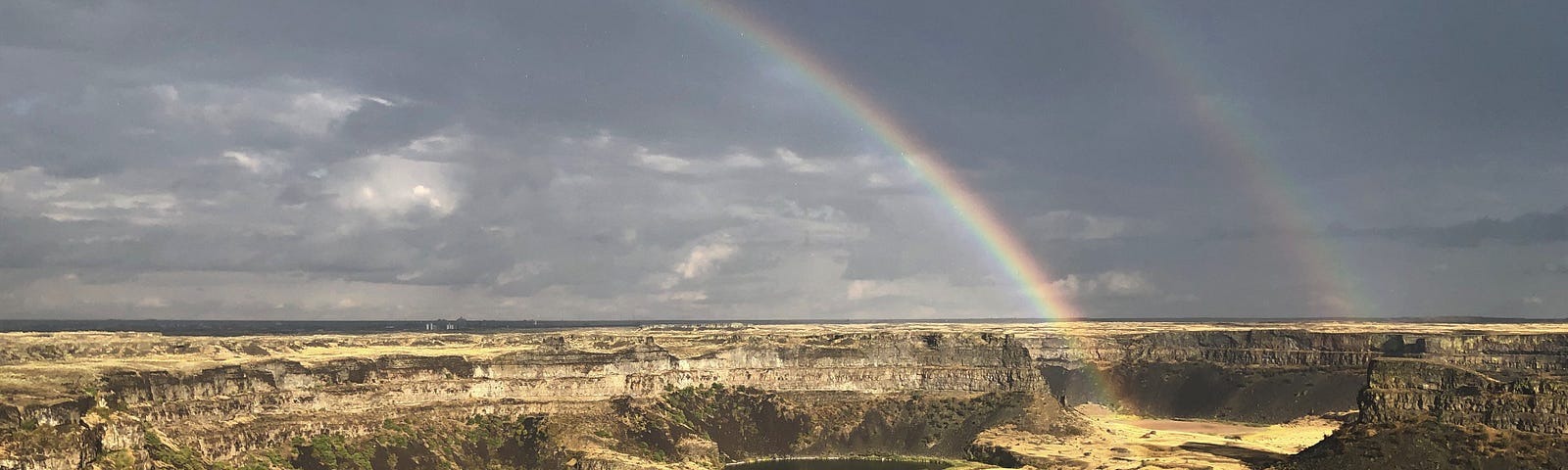 Lakes surrounded by cliffs, with two rainbows overhead