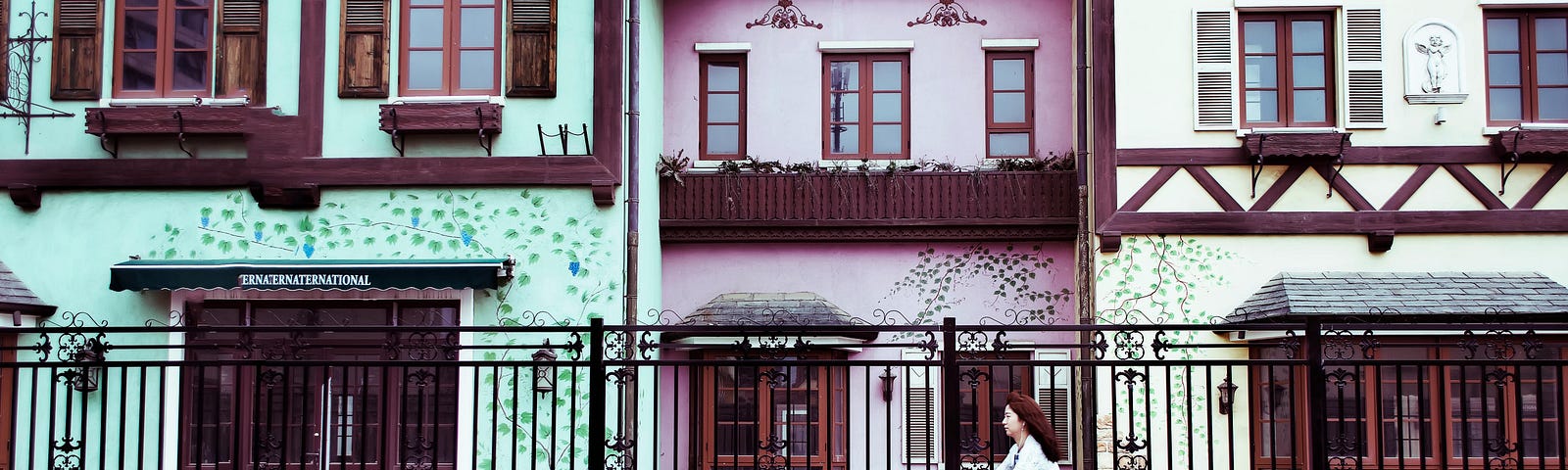 This shows a woman riding a bike in front of colorful buildings.