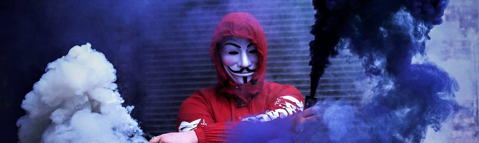 person in red hooded sweatshirt wearing mask and waving blue smoke flares