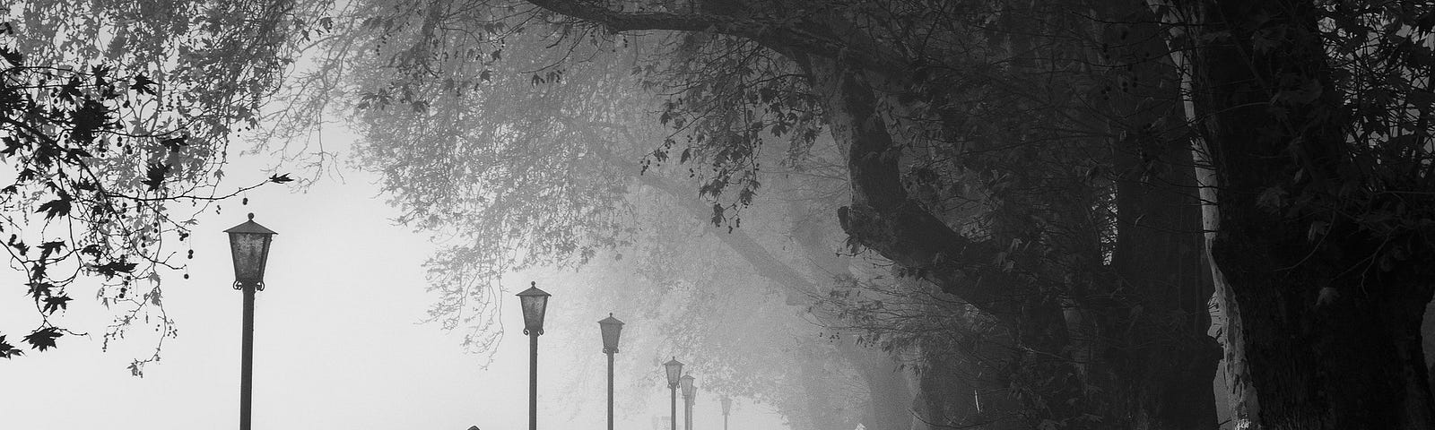 A mist filled strand where people are strolling with one man in foreground by himself
