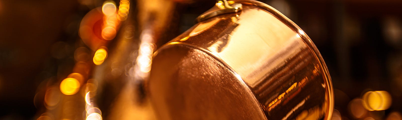 A hanging copper pot with other hanging pots in the background (blurred).