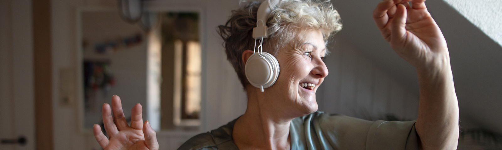 Older woman with white headphones on, arms raised, dancing. At top: Writing Prompt #31: What are your top self-care tips?