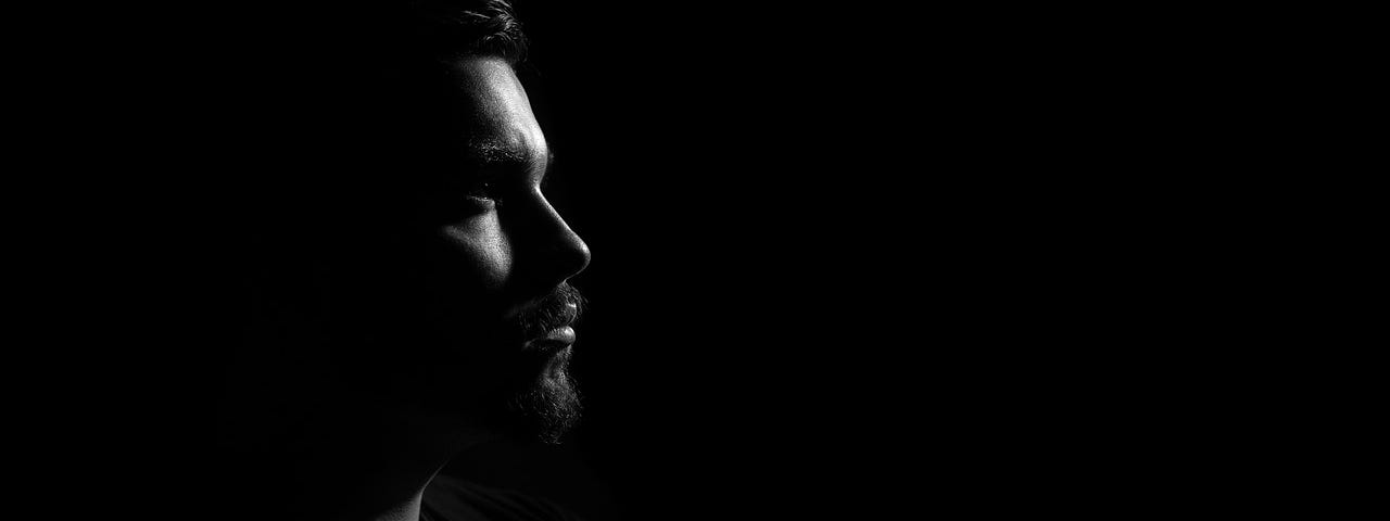 Man’s face partially lit in darkness