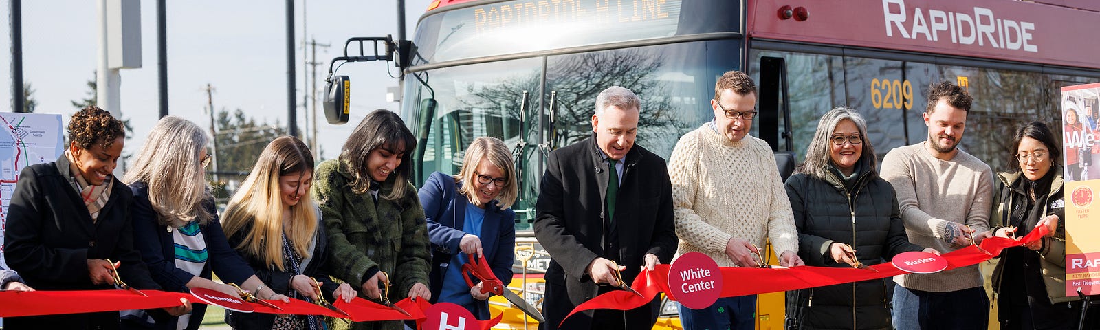 Executive Constantine and community leaders cut a red ribbon in front of a Metro bus, celebrating the launch of the RapidRide H Line.