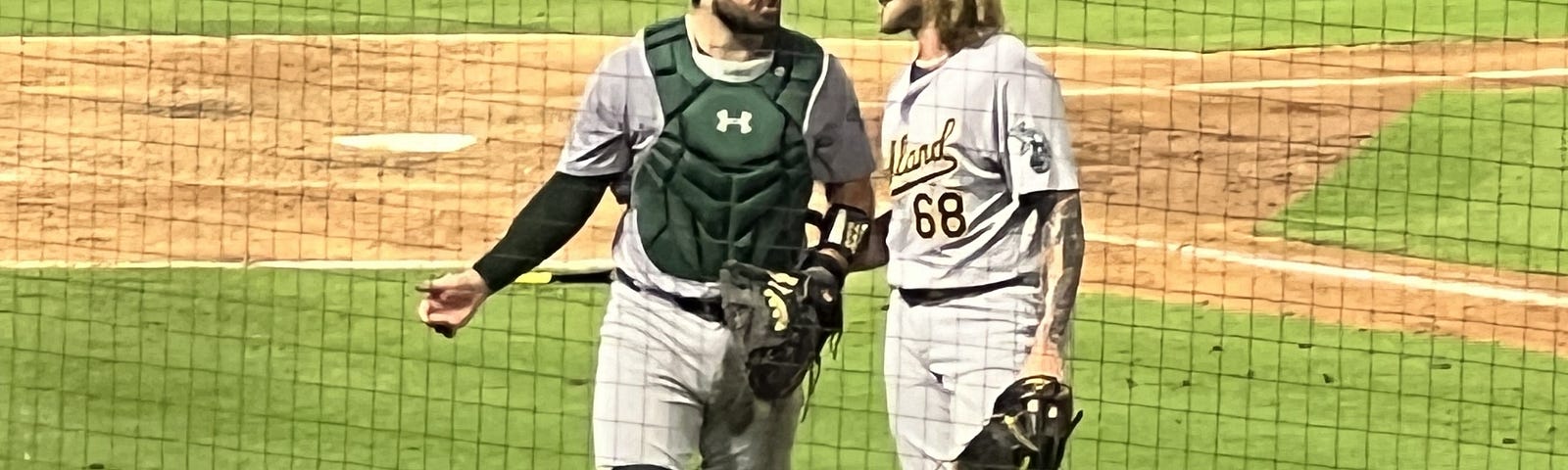 Oakland Athletics’ catcher Shea Langeliers talks with pitcher Joey Estes as they walk off the field from Angels Stadium.