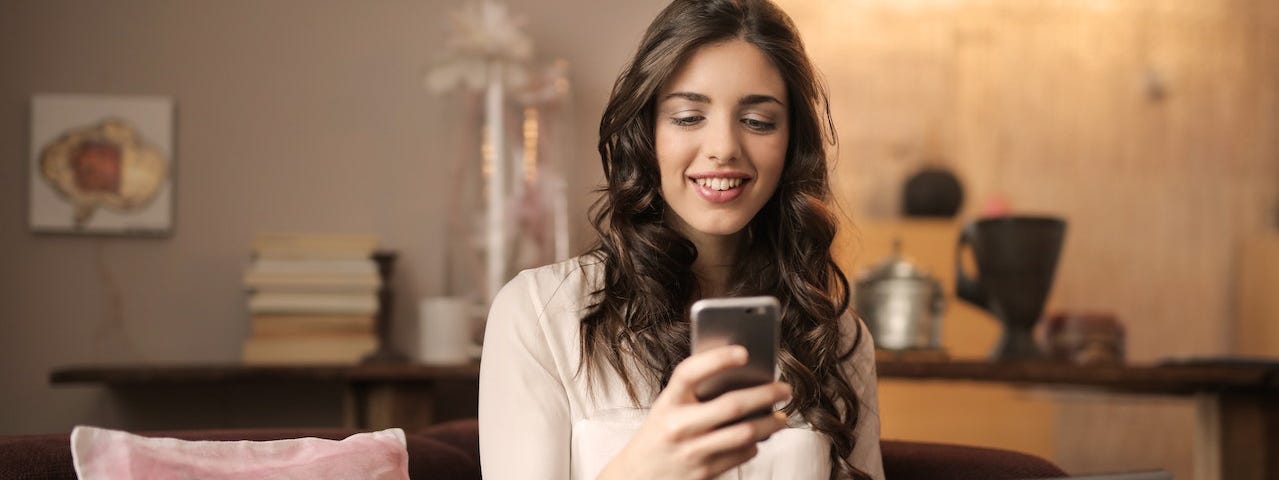 A woman looking at her phone and smiling slightly.