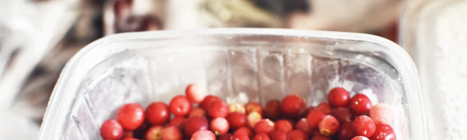 Frozen cranberries in an open plastic container.