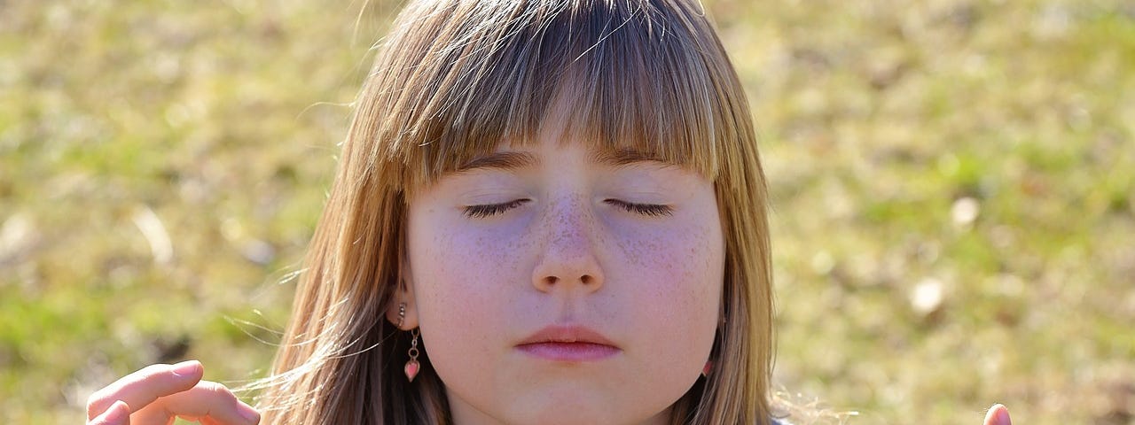 A girl doing meditation with her eyes closed.